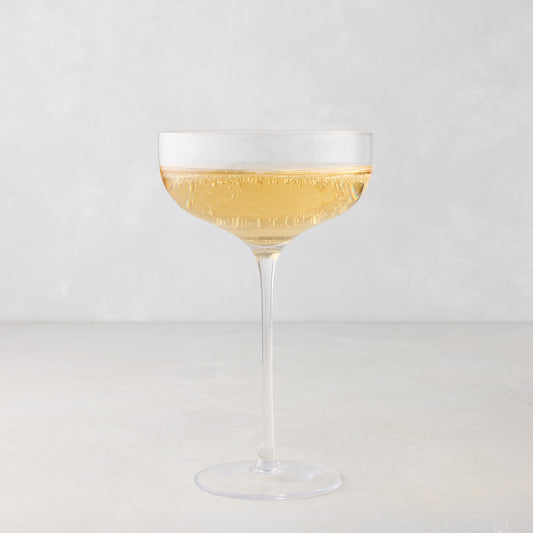 HG Heritage Coupe Glass, clear mouth-blown glass, filled with sparkling golden liquid.