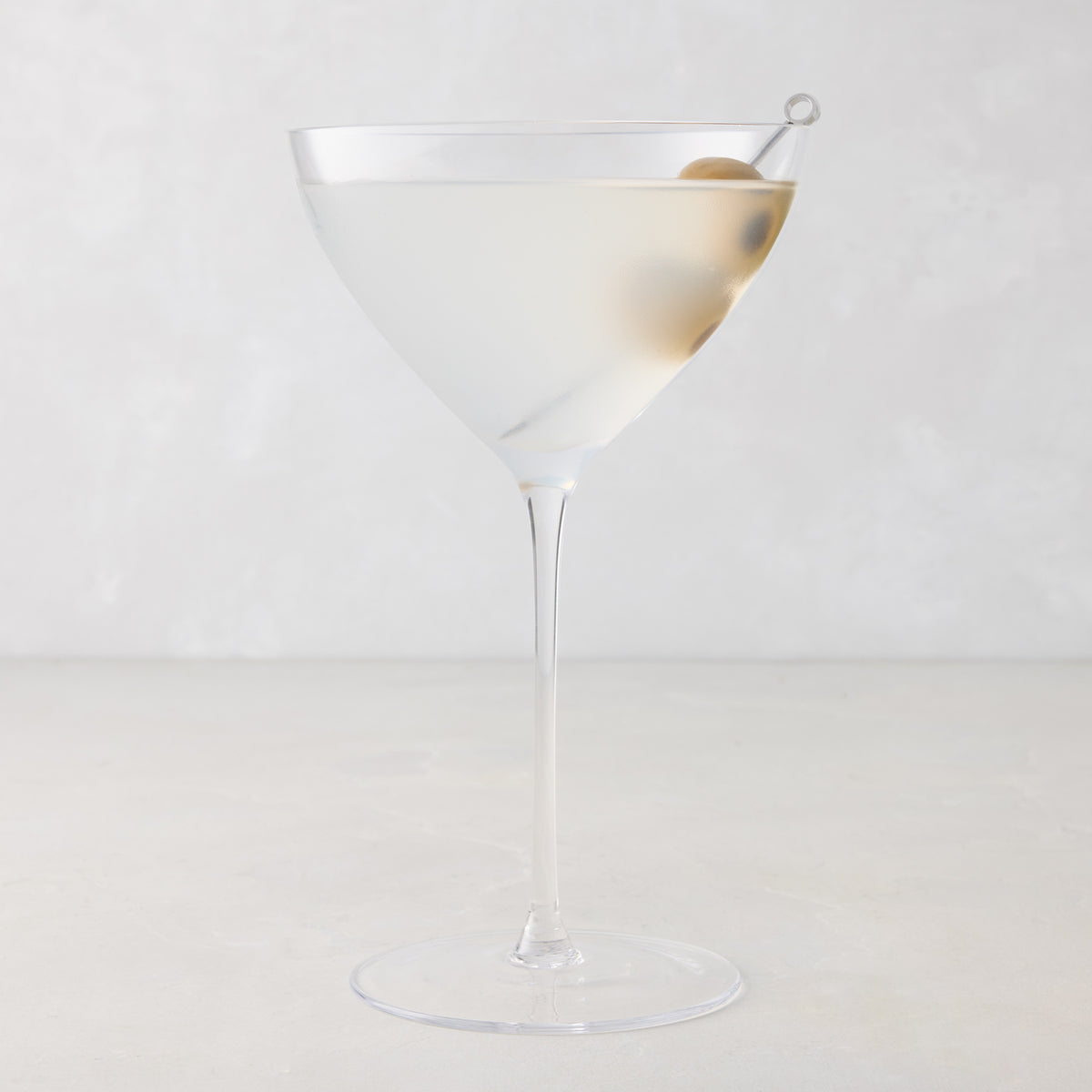 Oversized 14oz mouth-blown clear glass martini glass with a long stem and a single olive garnish.
