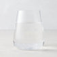 Clear HG Heritage Stemless Glass, mouth-blown, filled with water, on a light background.
