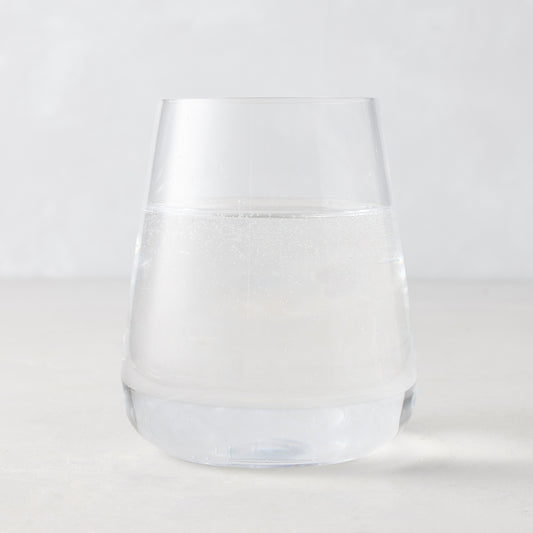 Clear HG Heritage Stemless Glass, mouth-blown, filled with water, on a light background.
