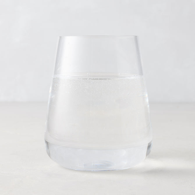 Clear HG Heritage Stemless Glass, mouth-blown, filled with water, on a light background.