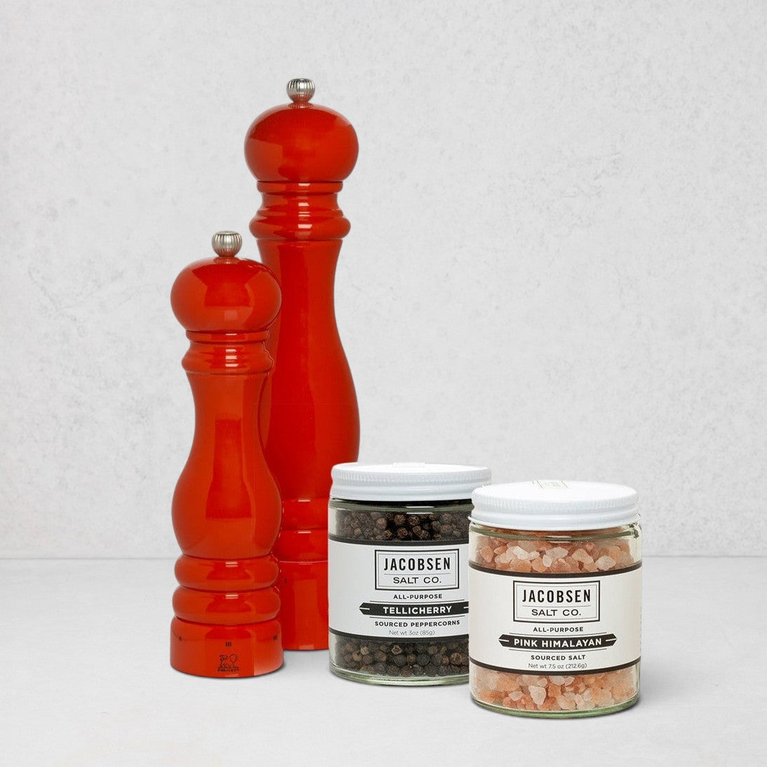 HG International Orange Salt & Pepper Gift Set: two red beechwood mills, Jacobsen Tellicherry peppercorns, and Pink Himalayan salt.
