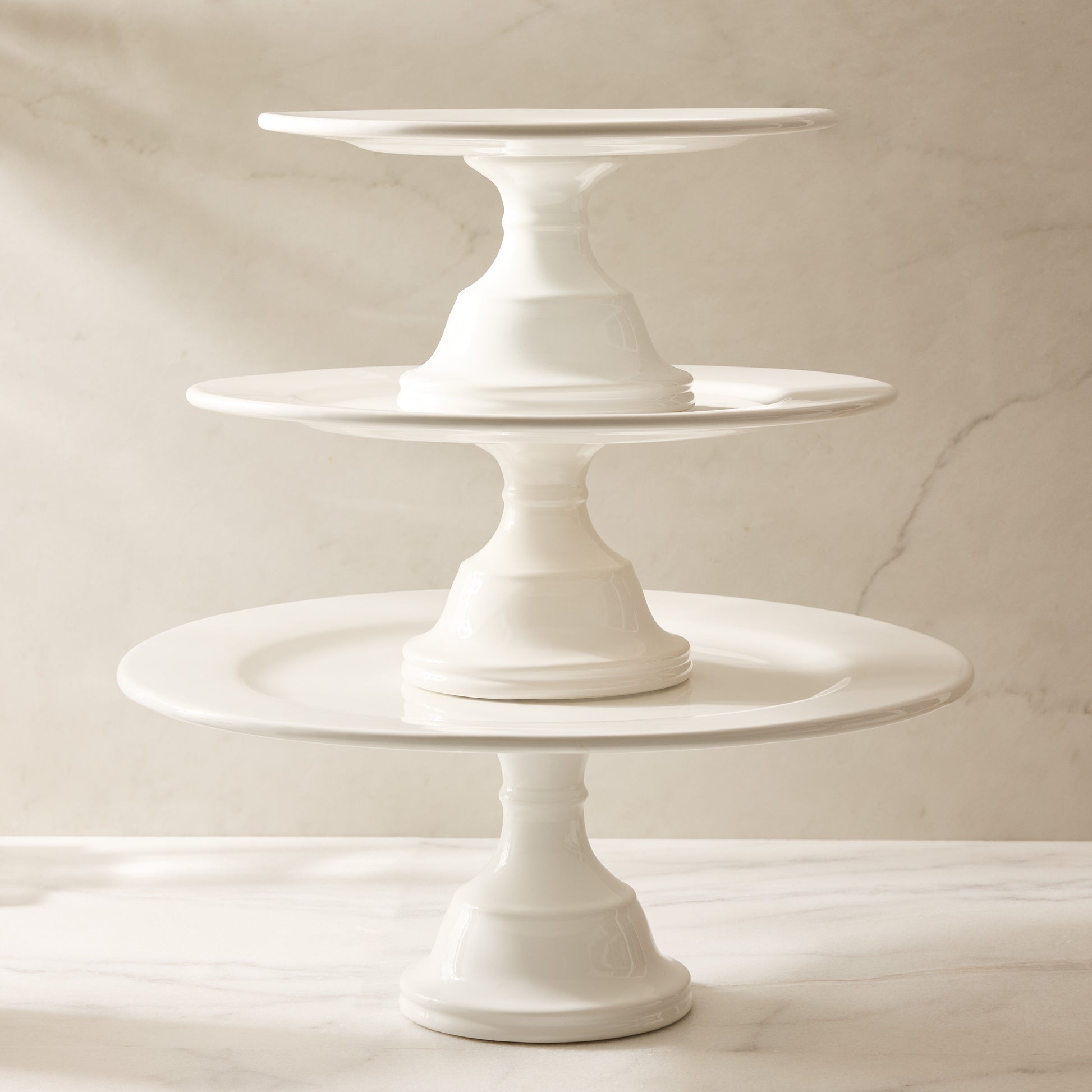 Three HG Original creamy white ceramic pedestal cake stands stacked, creating a tiered display.