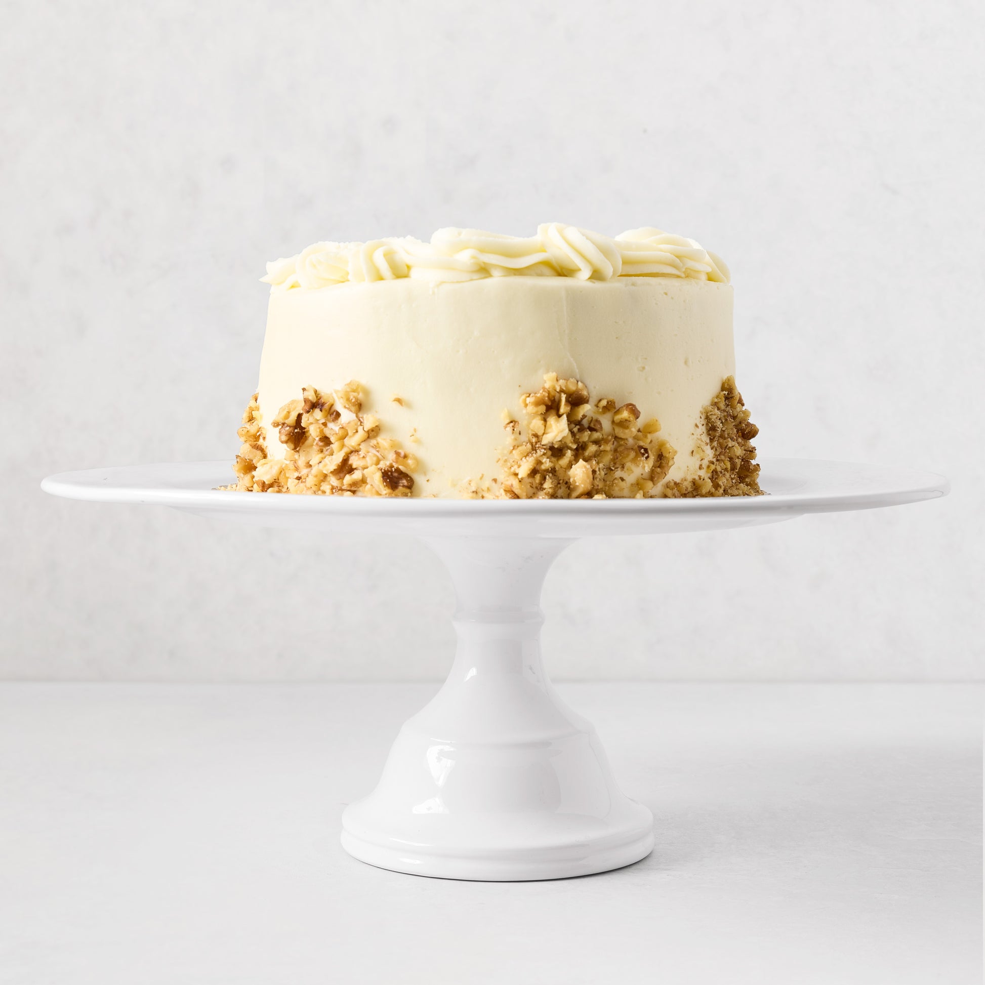 HG Original Large Pedestal Cake Stand, creamy white ceramic, 16"Dia x 6.5"H, holding a cake.