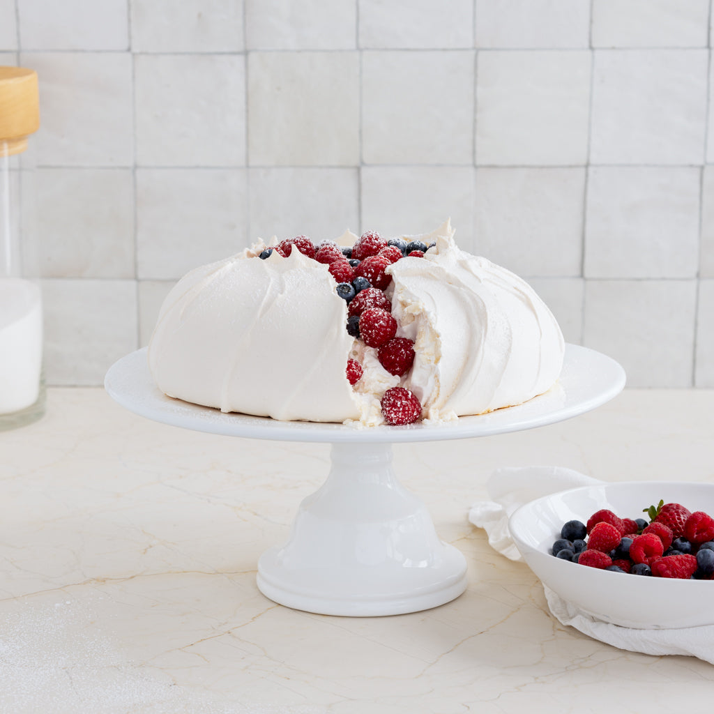 HG Original Medium Pedestal Cake Stand, creamy white ceramic, 13" diameter, 5.5" H, holding a pavlova.