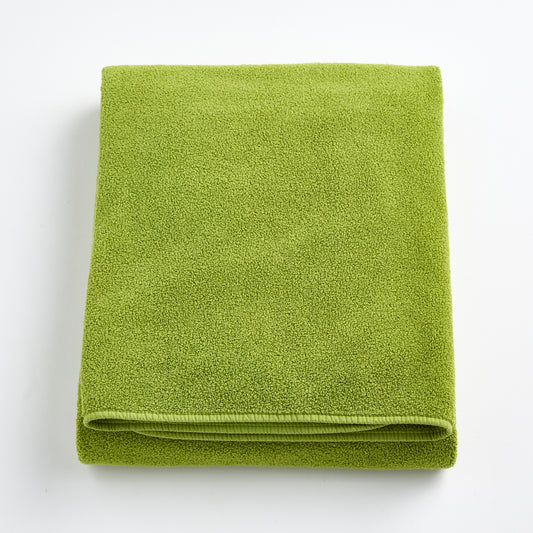 Folded aloe green bath sheet in zero twist cotton with matching bias piping, 40 by 70 inches.