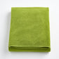 Folded aloe green bath sheet in zero twist cotton with matching bias piping, 40 by 70 inches.