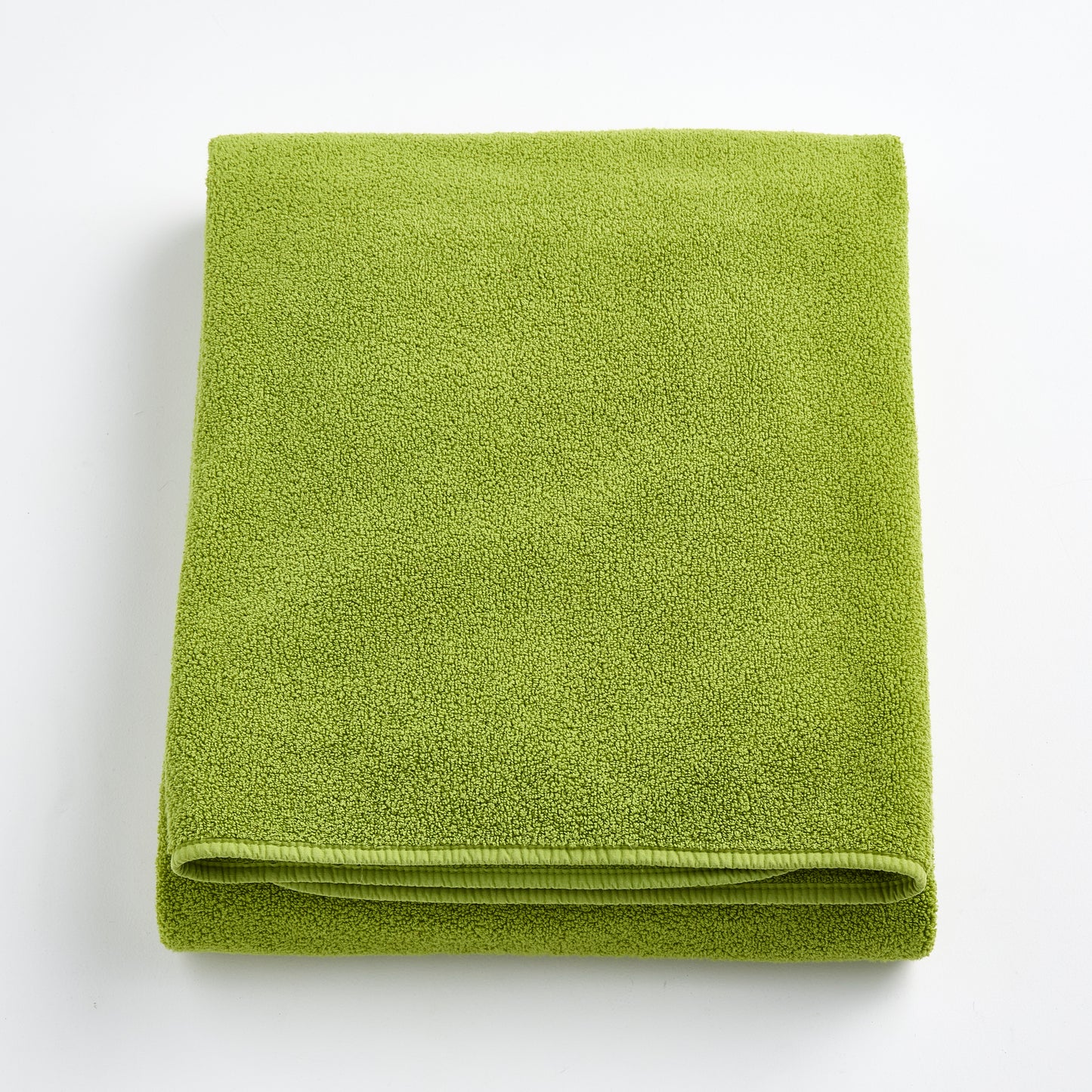 Folded aloe green bath sheet in zero twist cotton with matching bias piping, 40 by 70 inches.