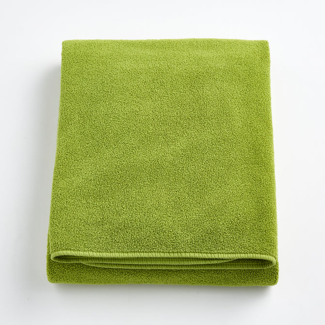 Folded aloe green bath sheet in zero twist cotton with matching bias piping, 40 by 70 inches.