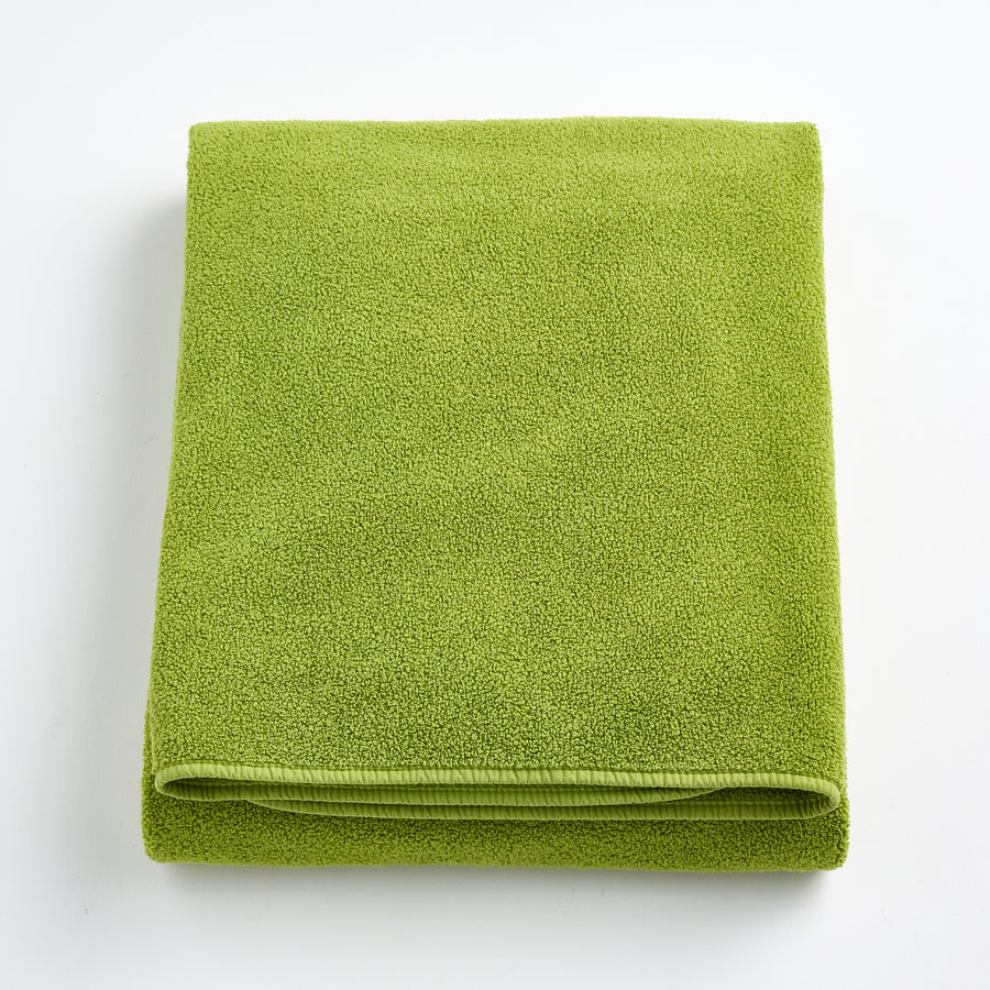 Folded aloe green bath sheet in zero twist cotton with matching bias piping, 40 by 70 inches.