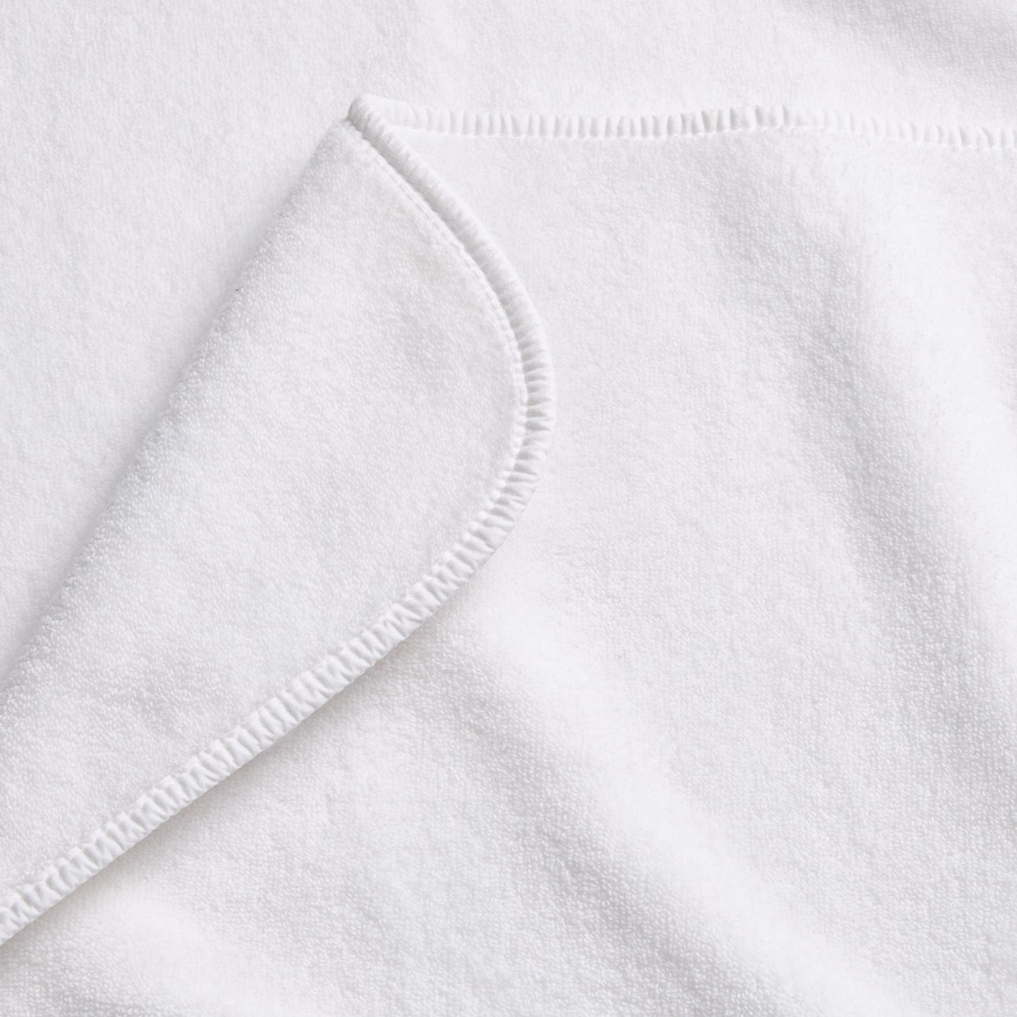 Cloud white Signature bath towel with a soft, plush cotton texture and a neatly finished rounded corner hem.