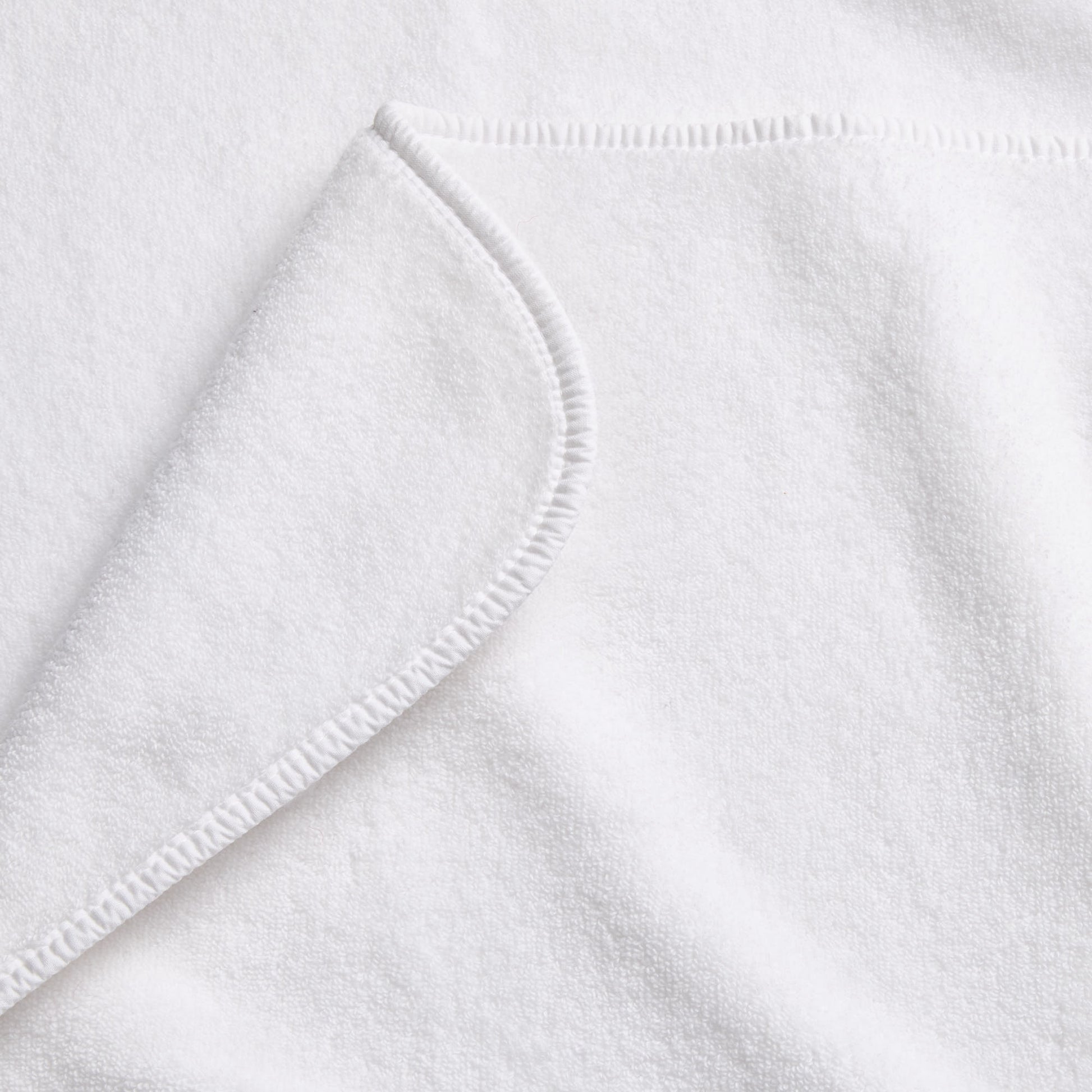 Cloud white Signature bath towel with a soft, plush cotton texture and a neatly finished rounded corner hem.
