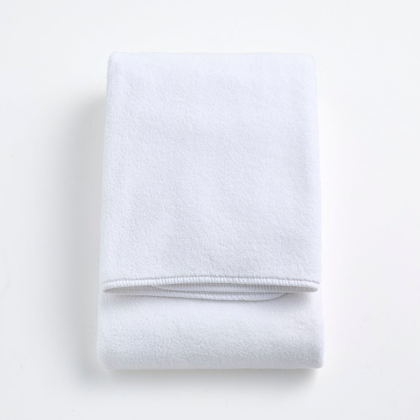 Folded cloud white signature bath towel made of plush, absorbent cotton fabric on a white background.