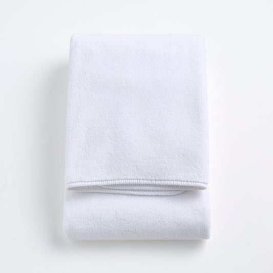 Folded cloud white signature bath towel made of plush, absorbent cotton fabric on a white background.