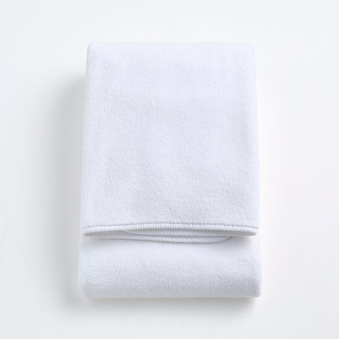 Folded cloud white signature bath towel made of plush, absorbent cotton fabric on a white background.