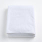 Folded cloud white Signature bath sheet made of plush, absorbent cotton terry fabric.