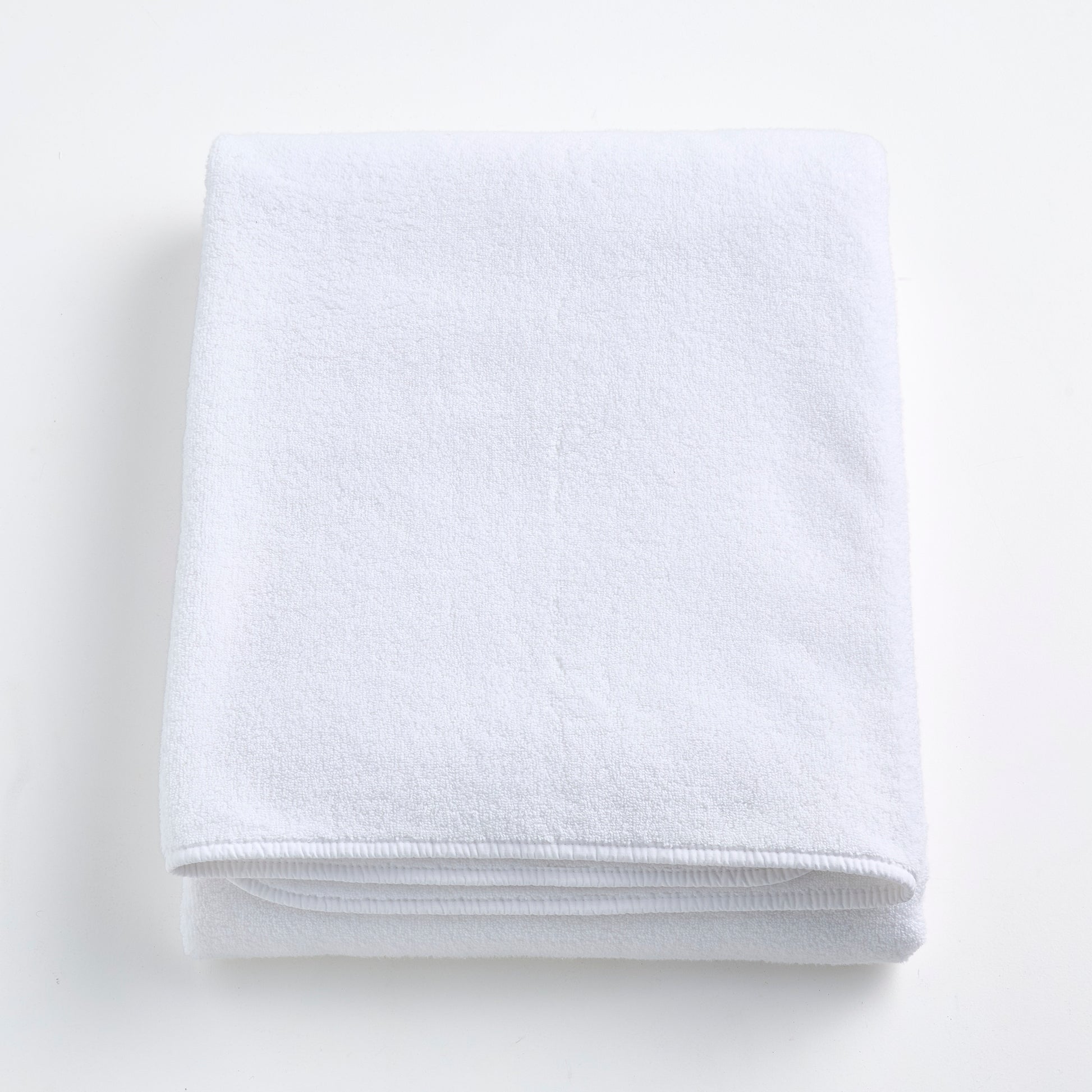 Folded cloud white Signature bath sheet made of plush, absorbent cotton terry fabric.
