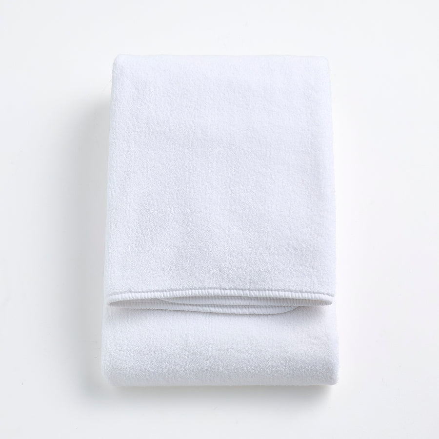 Folded cloud white signature bath towel made of plush, absorbent cotton fabric on a white background.