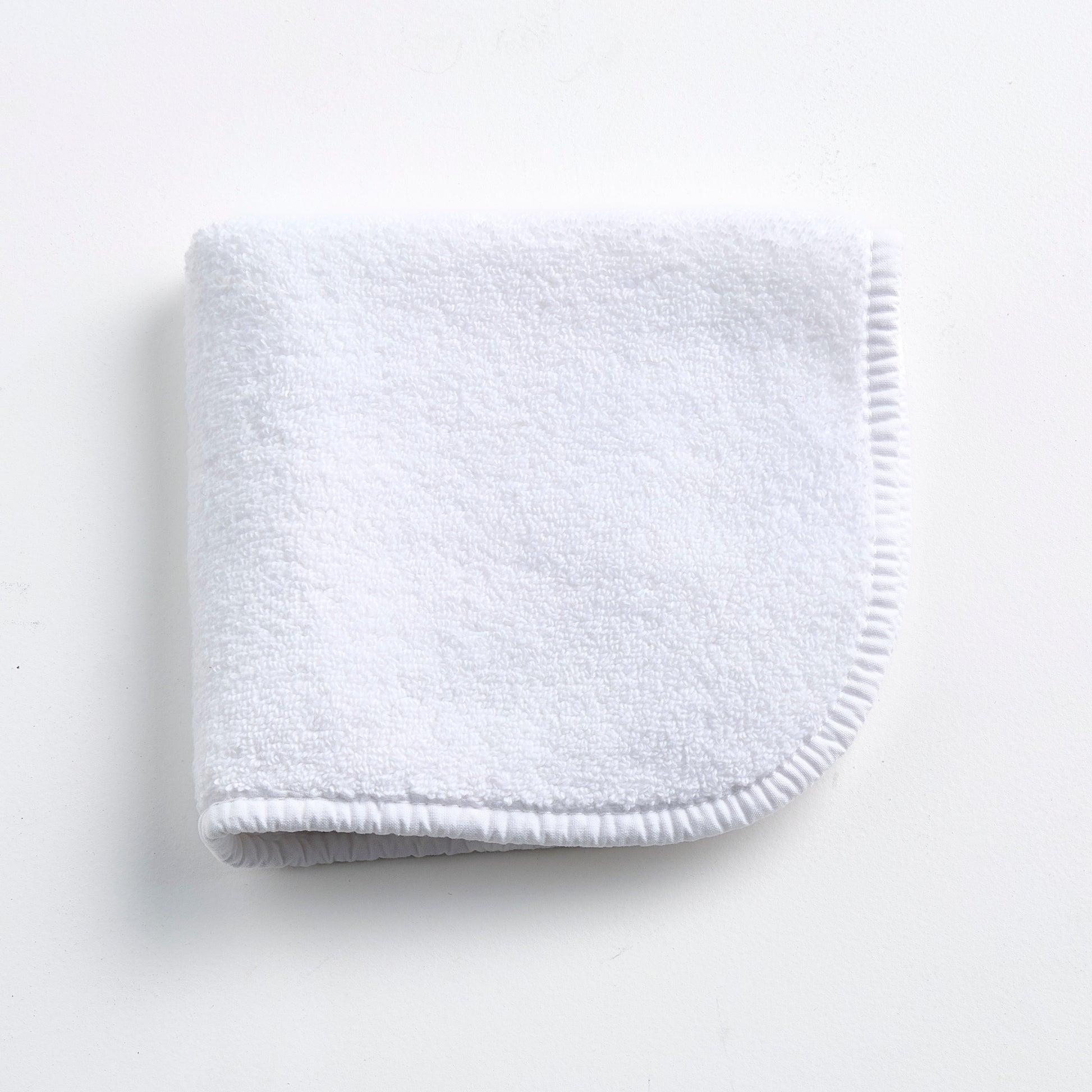 Cloud white Signature washcloth in soft, absorbent terry cotton with rounded corners and a finished piped edge.