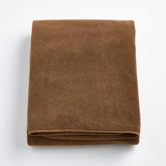 Folded coffee brown cotton bath sheet with a soft, plush texture and finished hem on a white background.