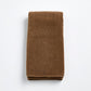 Folded coffee brown cotton hand towel with a soft, plush terry texture on a white background.