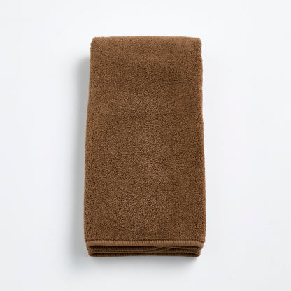 Folded coffee brown cotton hand towel with a soft, plush terry texture on a white background.