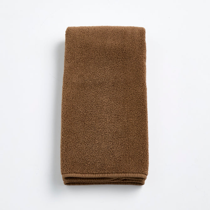 Folded coffee brown cotton hand towel with a soft, plush terry texture on a white background.