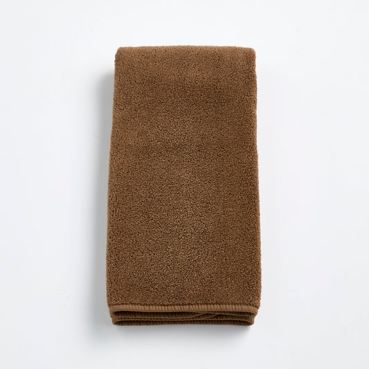 Folded coffee brown cotton hand towel with a soft, plush terry texture on a white background.