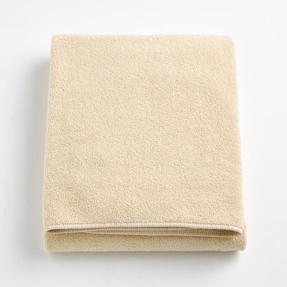 Folded creme brulee signature bath sheet in plush, textured cotton terry fabric on a white background.