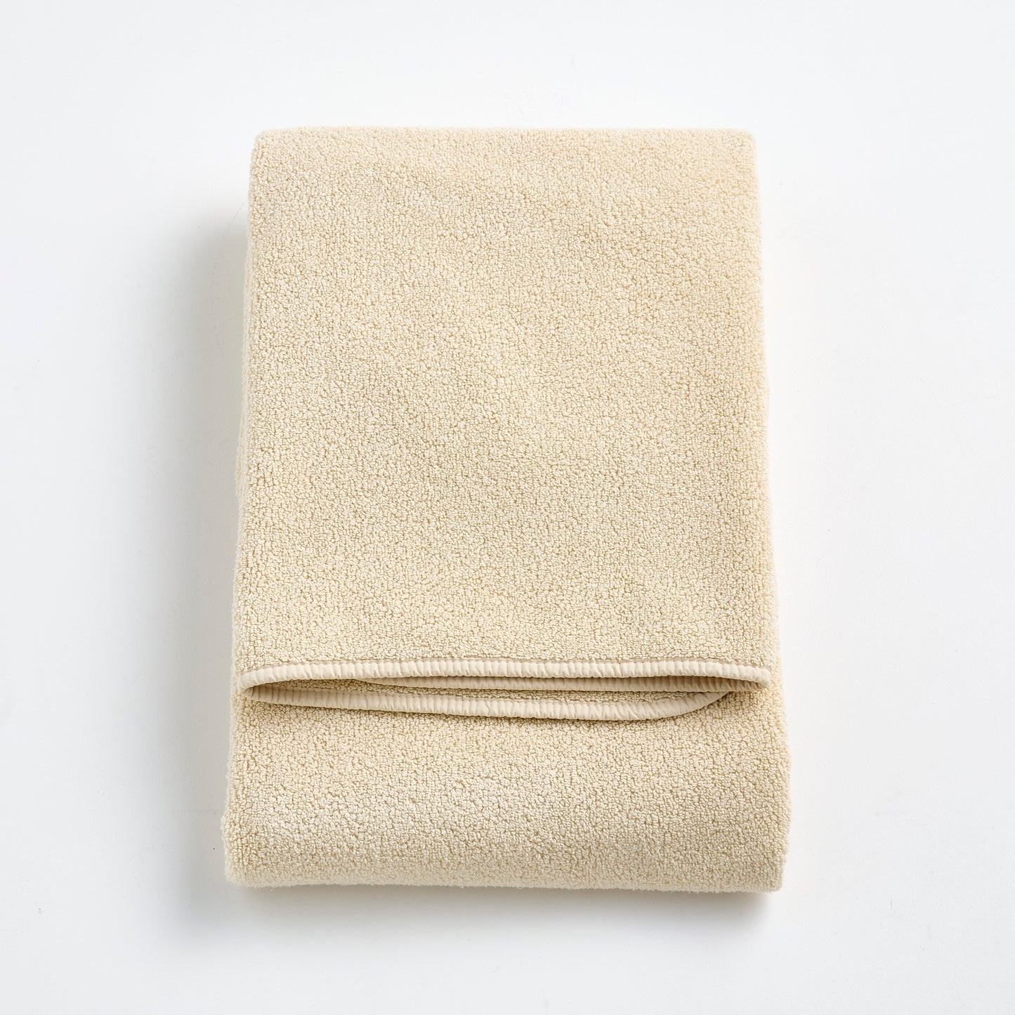 Folded Signature bath towel in creme brulee beige with a plush, textured cotton weave and finished edges.