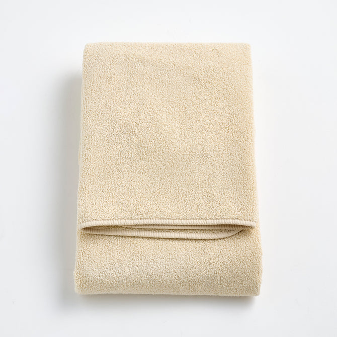 Folded Signature bath towel in creme brulee beige with a plush, textured cotton weave and finished edges.