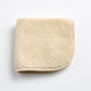 Creme brulee signature washcloth with a soft, textured terry cotton finish and rounded stitched edges.