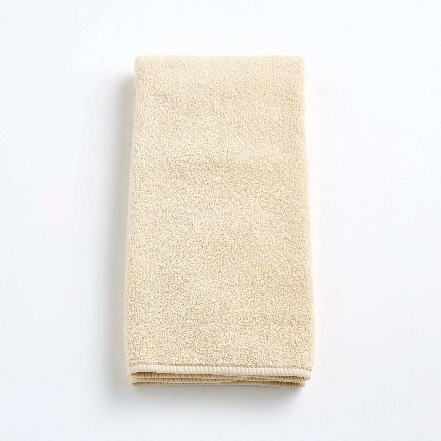 Folded creme brulee signature hand towel in soft, textured cotton terry cloth on a white background.