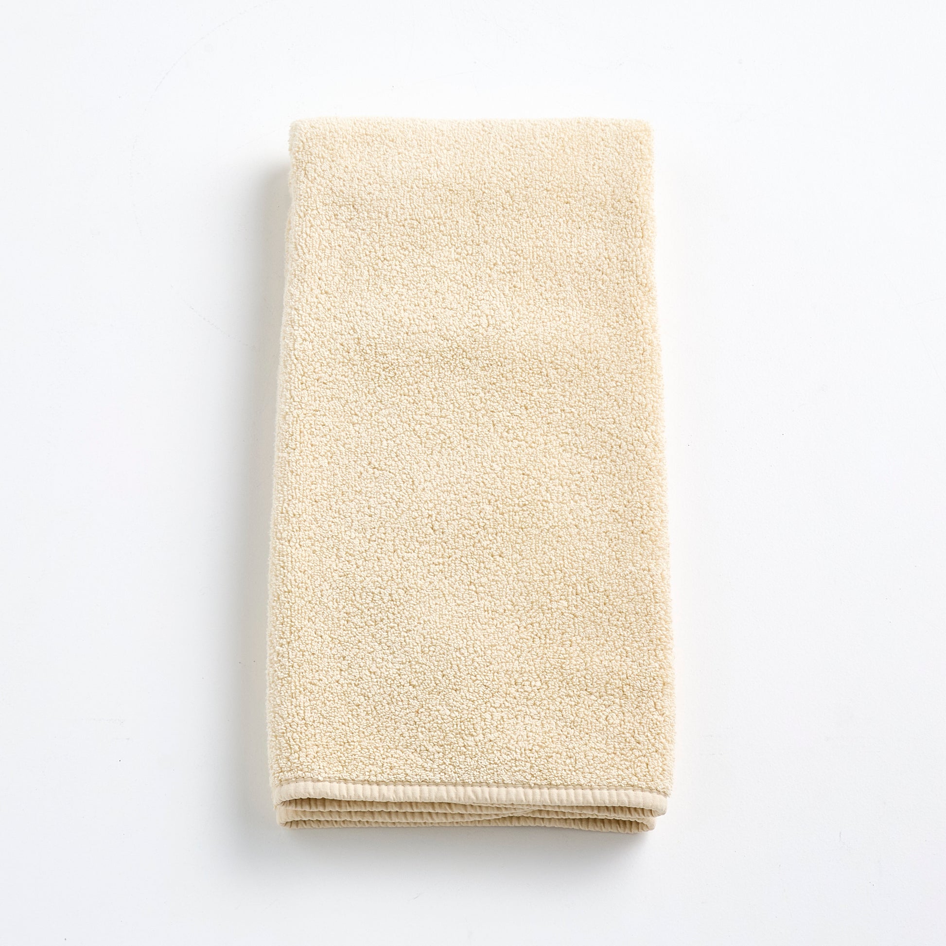 Folded creme brulee signature hand towel in soft, textured cotton terry cloth on a white background.
