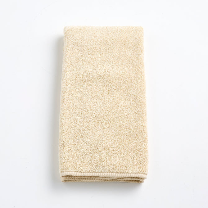 Folded creme brulee signature hand towel in soft, textured cotton terry cloth on a white background.