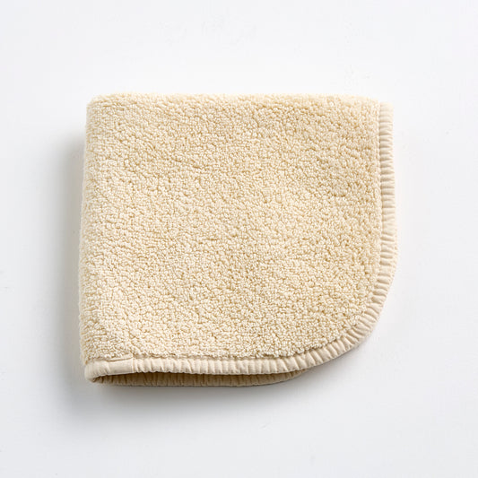 Creme brulee signature washcloth with a soft, textured terry cotton finish and rounded stitched edges.