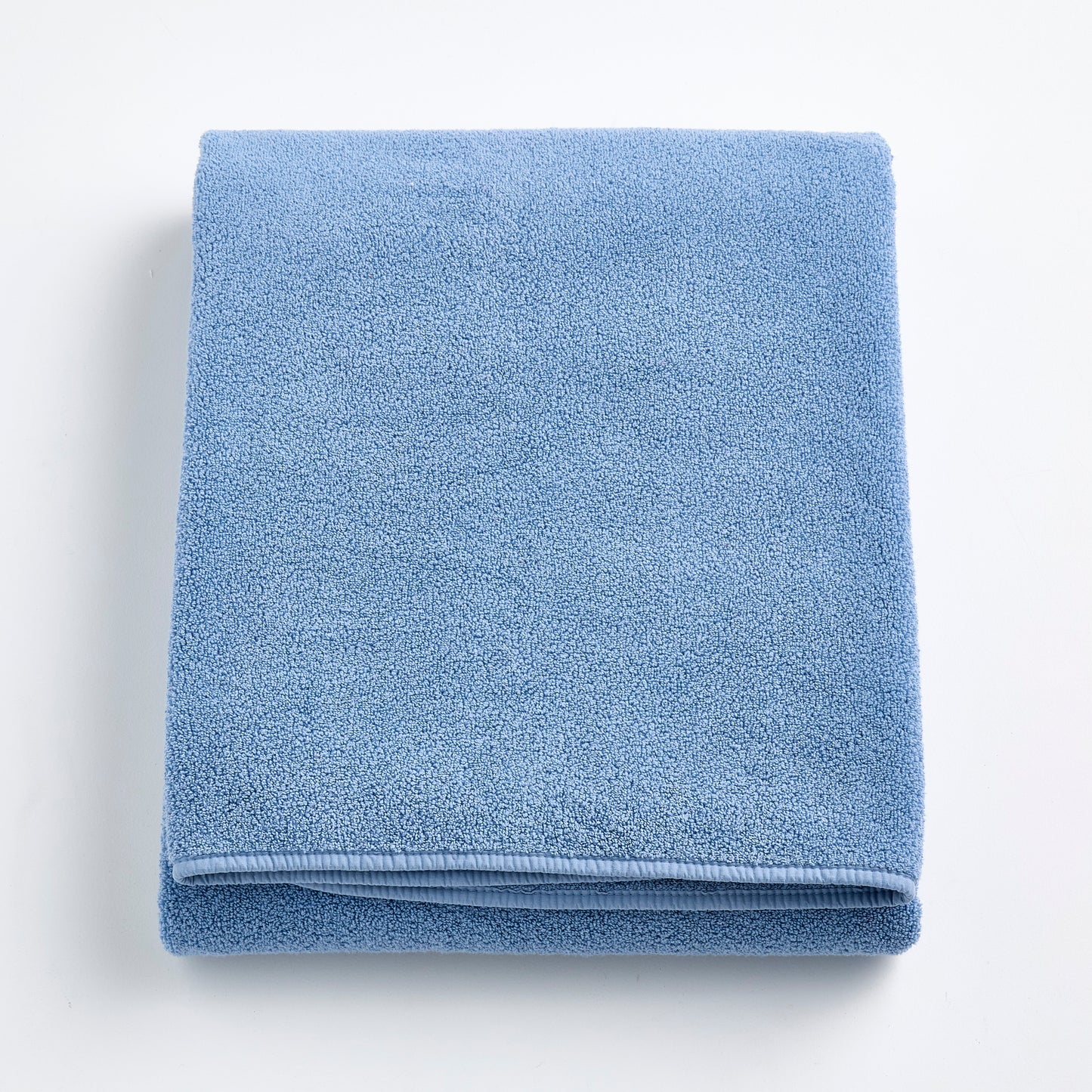 Folded denim blue Signature bath sheet in plush, absorbent cotton terry fabric with a clean hemmed edge.