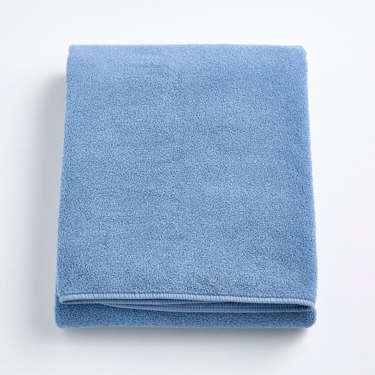 Folded denim blue Signature bath sheet in plush, absorbent cotton terry fabric with a clean hemmed edge.