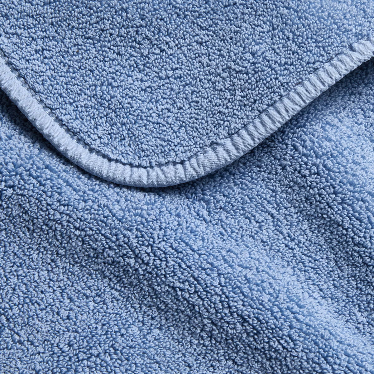 Denim blue Signature hand towel featuring a soft, plush cotton terry texture and a finished stitched edge.