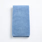 Folded denim blue cotton hand towel with a textured terry cloth finish on a white background.