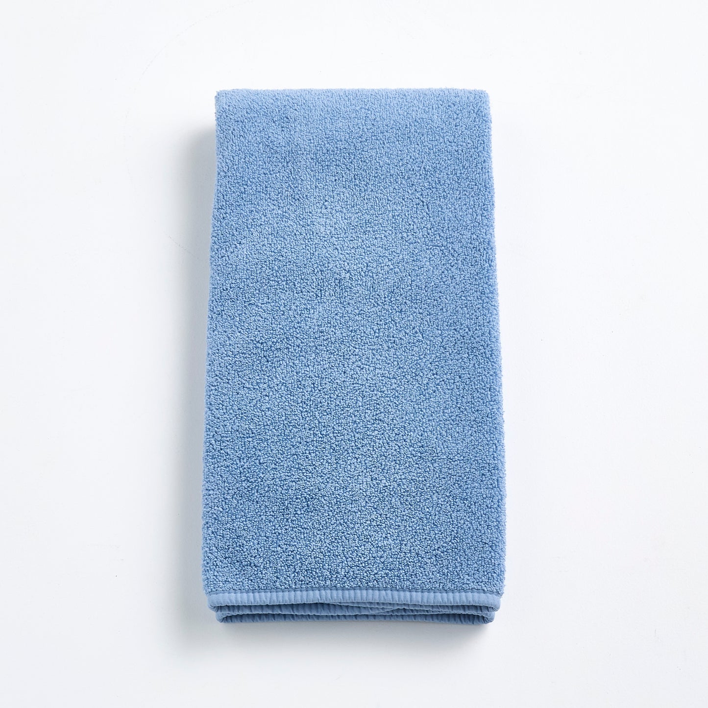 Folded denim blue cotton hand towel with a textured terry cloth finish on a white background.