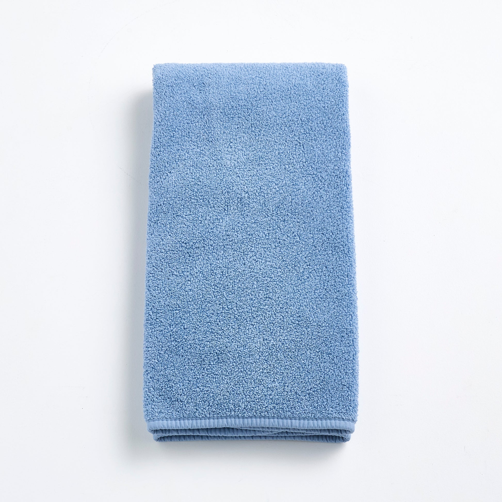 Folded denim blue cotton hand towel with a textured terry cloth finish on a white background.