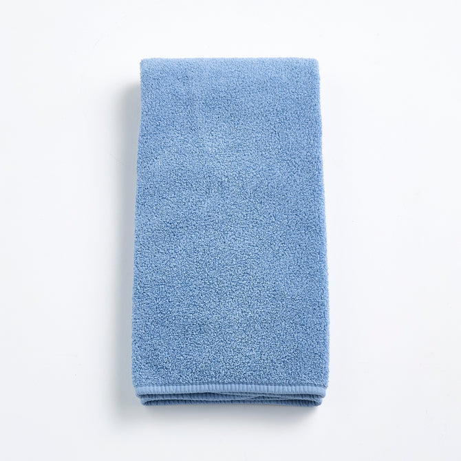 Folded denim blue cotton hand towel with a textured terry cloth finish on a white background.