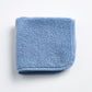 Folded denim blue cotton terry washcloth with a matching stitched border on a white background.
