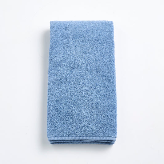 Folded denim blue cotton hand towel with a textured terry cloth finish on a white background.