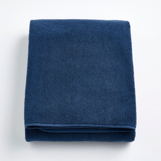 Folded indigo blue Signature bath sheet made of plush, absorbent cotton terry fabric.