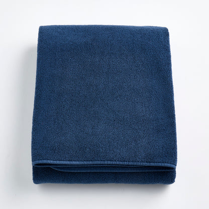 Folded indigo blue Signature bath sheet made of plush, absorbent cotton terry fabric.
