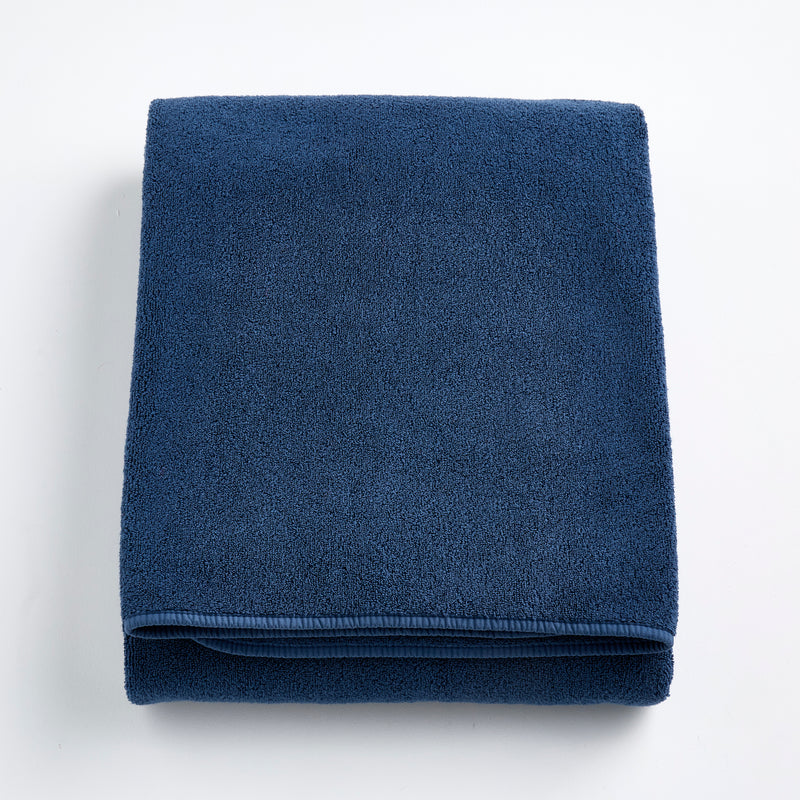 Folded indigo blue Signature bath sheet made of plush, absorbent cotton terry fabric.
