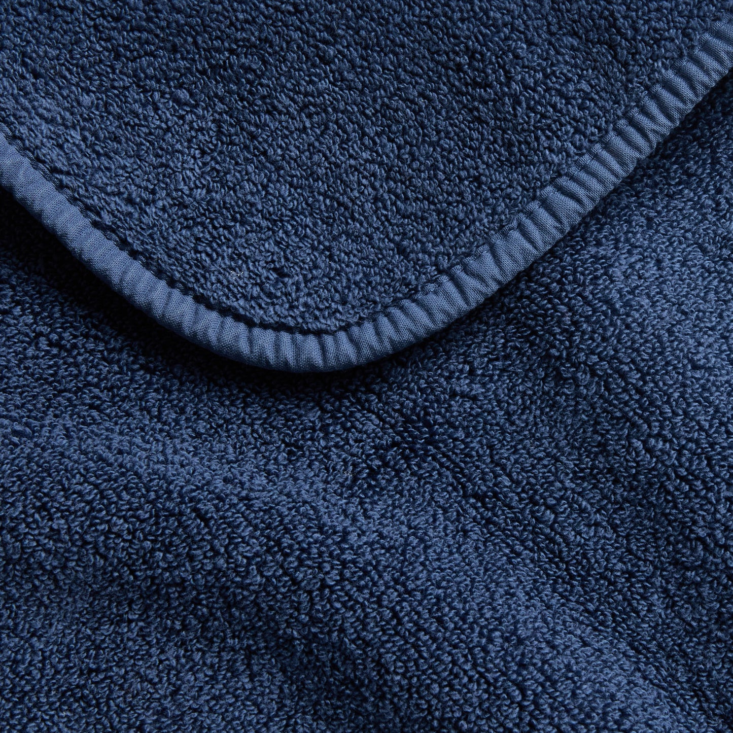 Indigo blue bath towel in soft, plush cotton terry fabric with a finished stitched hem edge.