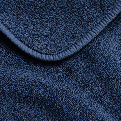 Indigo blue hand towel with a soft, plush terry cloth texture and a finished stitched edge.